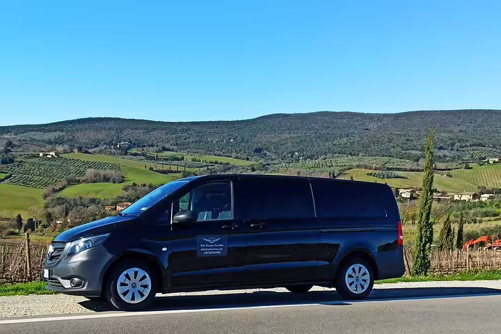 Private Chianti wine tour minivan parked by Tuscan hills and vineyards under a clear blue sky in the countryside