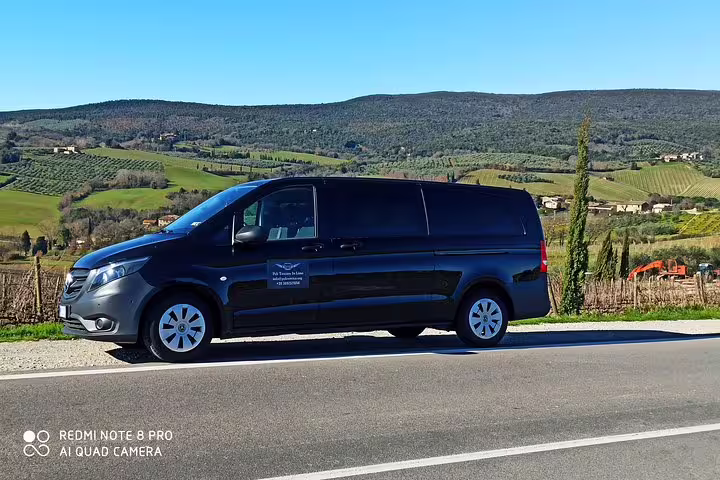 Comfortable black minivan for private Cortona and Montepulciano art and wine tour parked amid Tuscan countryside