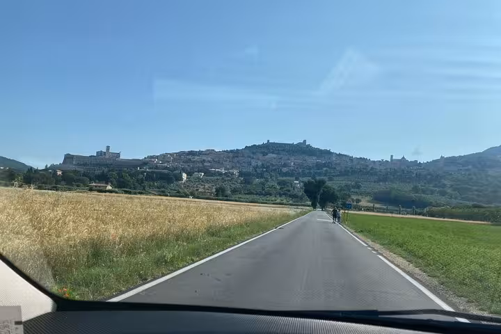 Scenic drive towards Assisi with a view of the historic town and lush countryside on a private day tour from Rome.