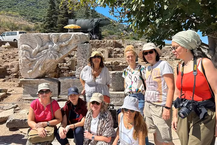 Cruise guests on private Ephesus tour beside carved marble relief ruins, skip-the-line guided shore excursion