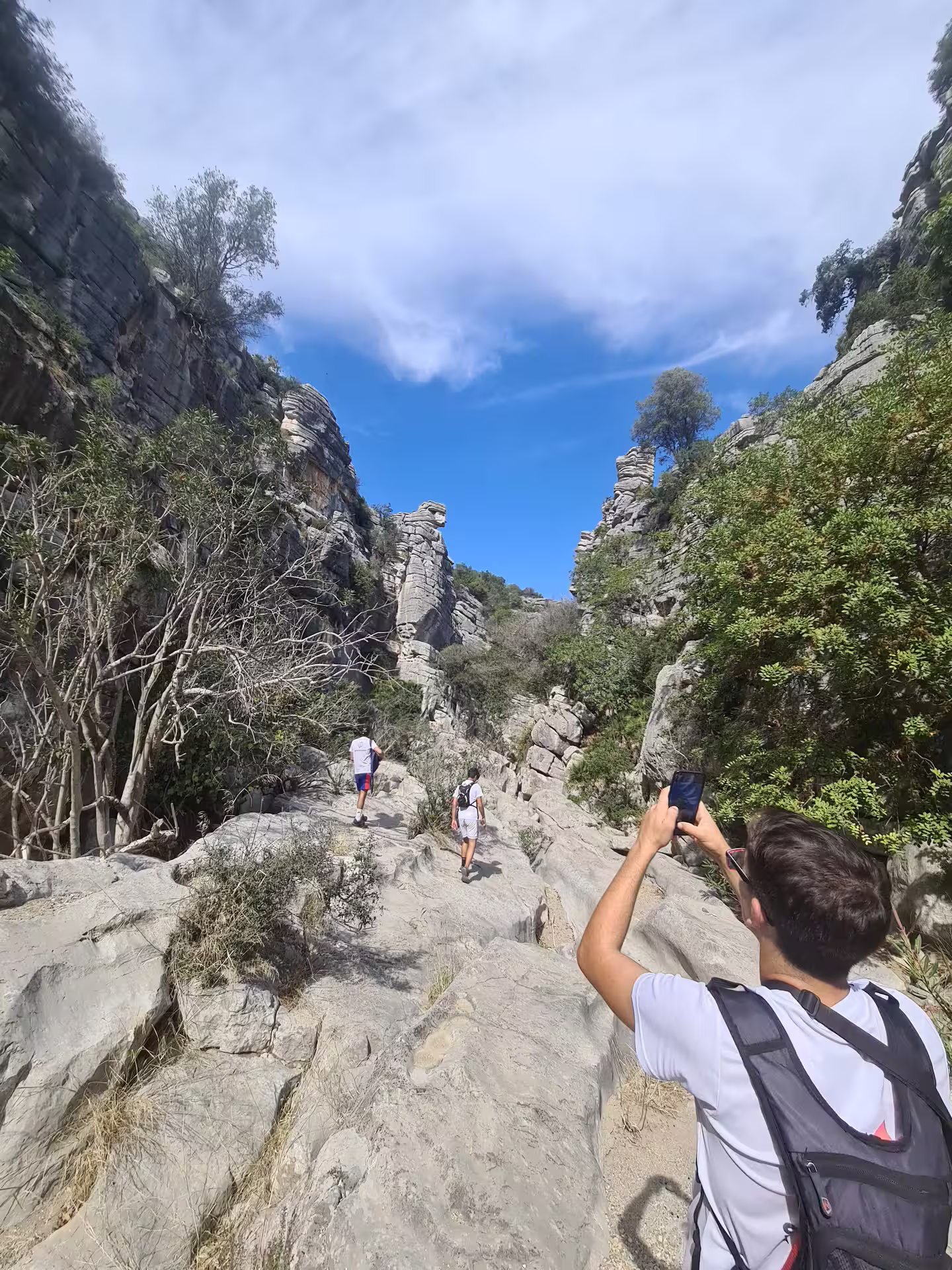 Tourists capturing scenic views of rugged cliffs and lush greenery during a private hike at Canuto de la Utrera.