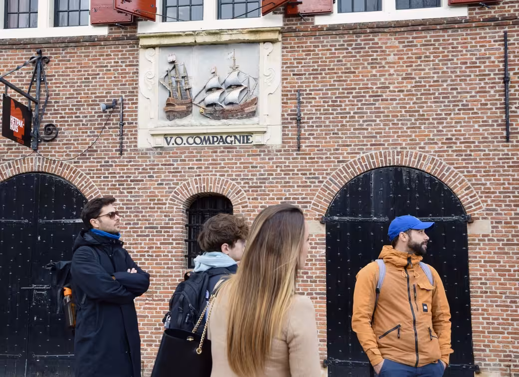 Travelers on private Hoorn history walking tour viewing VOC Compagnie facade on brick warehouse in Netherlands