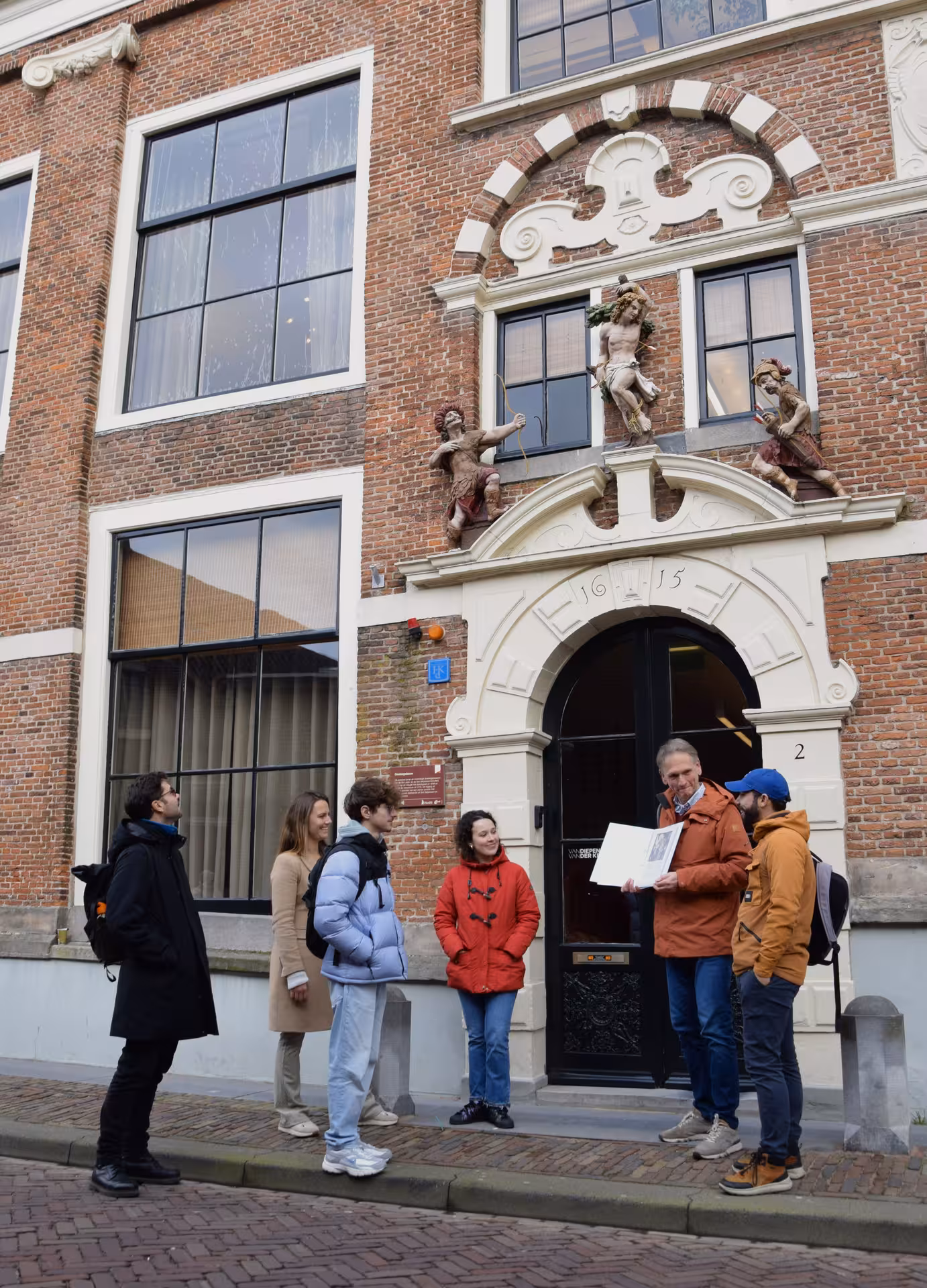 Private Hoorn walking tour group with guide outside historic Dutch building with ornate gable and statues