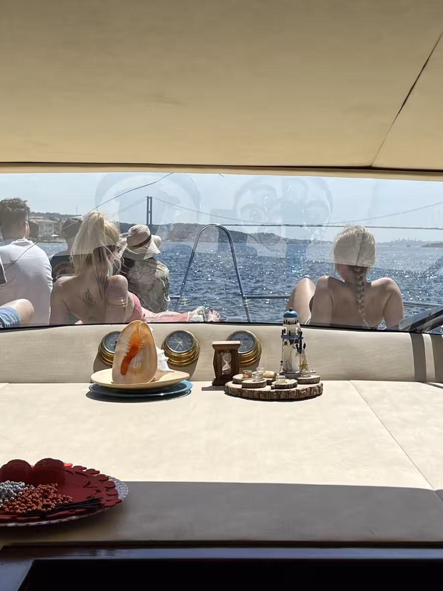 Guests relax on a private Istanbul yacht with snacks, cruising the Bosphorus near the suspension bridge