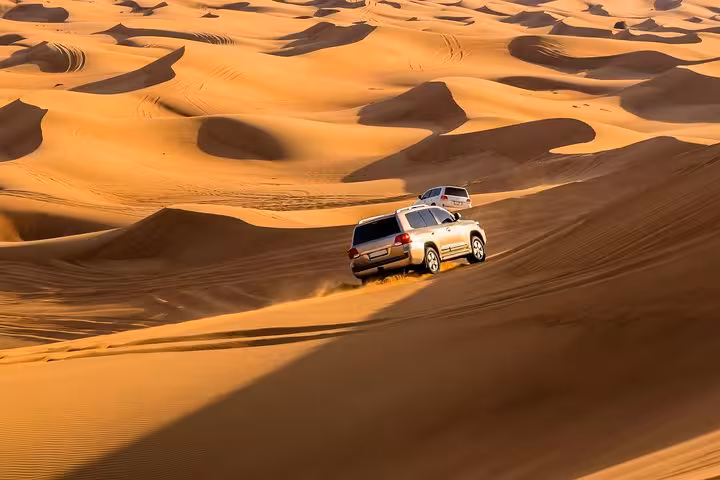 4x4 vehicles navigating golden dunes, showcasing thrilling dune bashing adventure on a private Liwa desert safari.