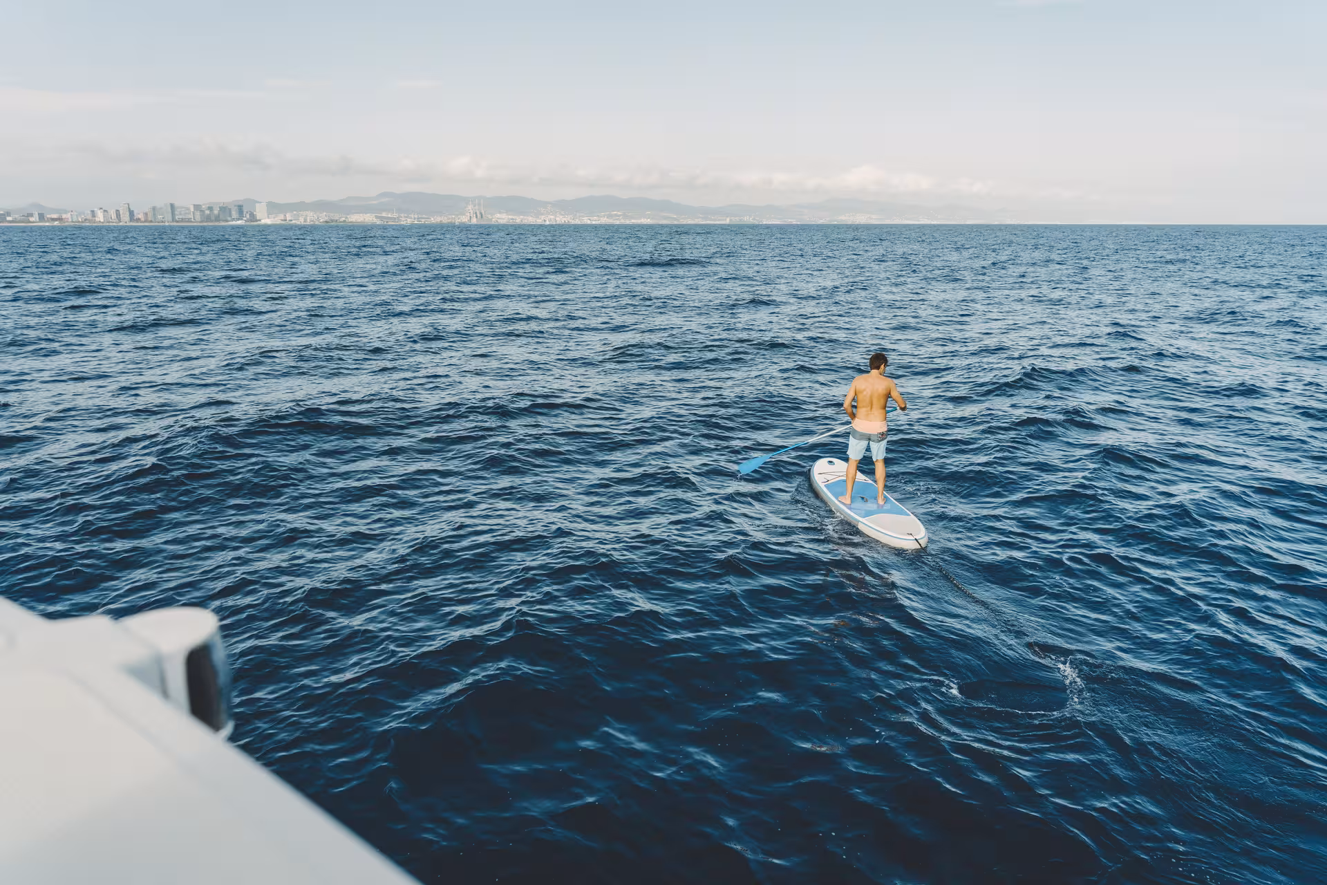 Guest paddleboarding in the Mediterranean during a 2-hour private luxury catamaran Barcelona tour on Bali 4.2
