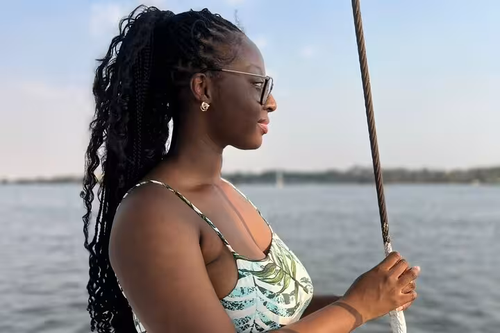 Woman enjoying Cairo Nile River private birthday boat cruise, holding rigging and watching sunset views