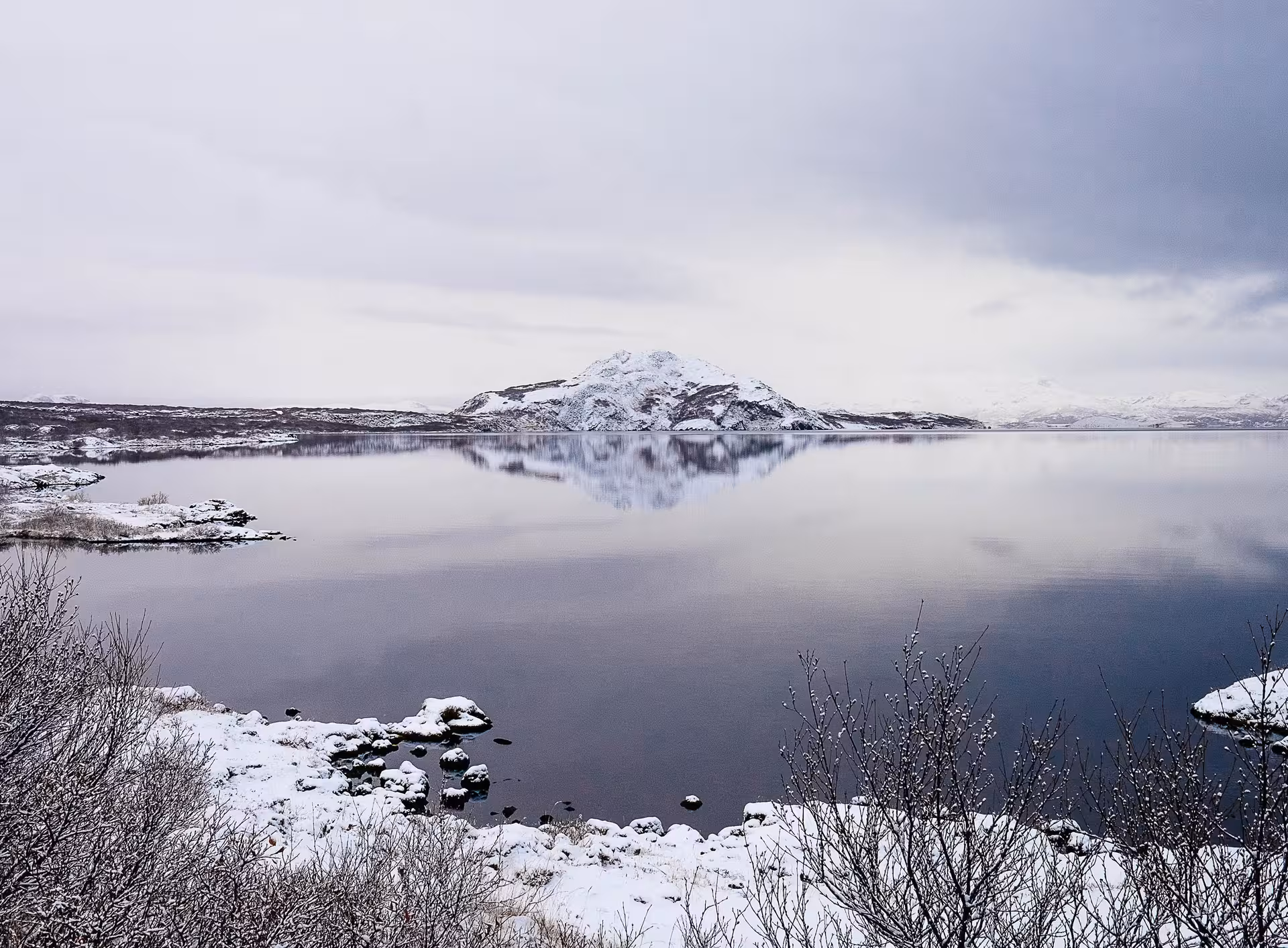Serene snowy mountain reflected in a calm lake, ideal for a private Northern Lights 4x4 Super Truck journey.