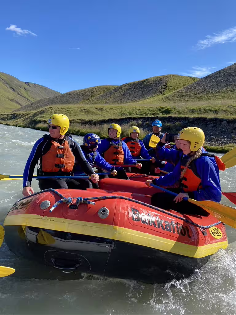 Adventurers enjoy private rafting on West Glacial River under clear skies, with scenic views near Akureyri, Iceland.