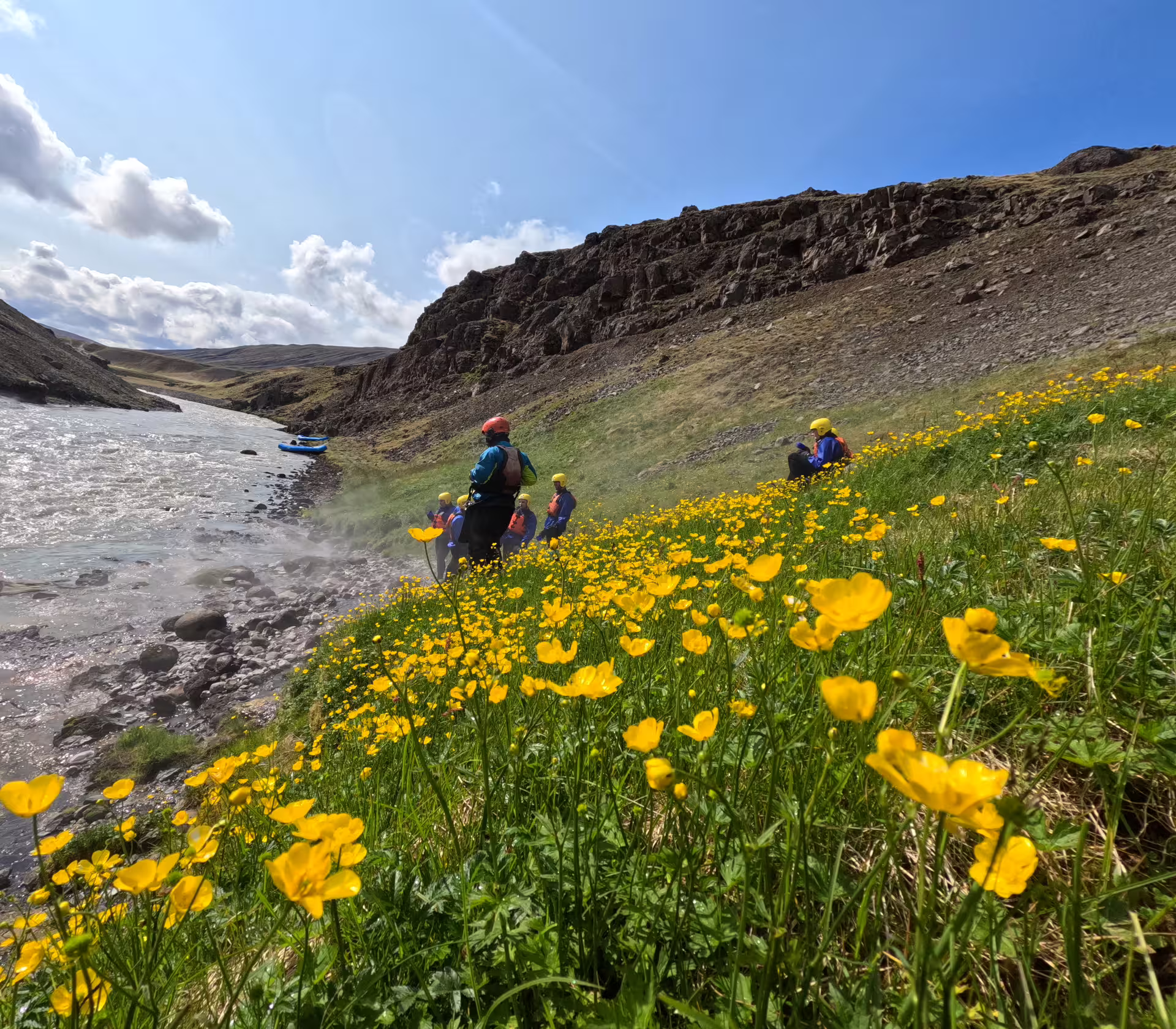 Adventurers in helmets prepare for a private rafting experience on West Glacial River, surrounded by vibrant wildflowers near Akureyri.