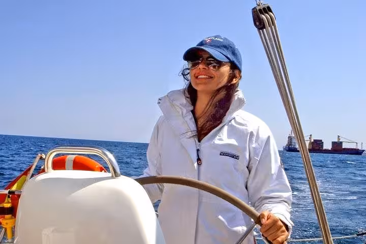 Guest steering a private sailboat off Barcelona with open bar and snacks, cruising the Mediterranean