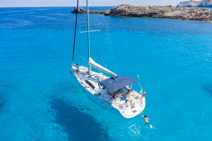 Private sailing tour near Barcelona with catamaran anchored in turquoise water, guests swimming and relaxing