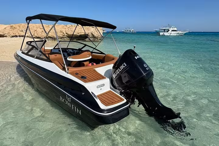 Private speedboat anchored in shallow turquoise water at Orange Bay Island, Hurghada snorkeling tour