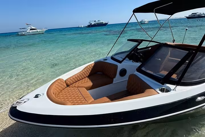 Private speedboat anchored in shallow turquoise water near Orange Bay Island, Hurghada snorkeling trip