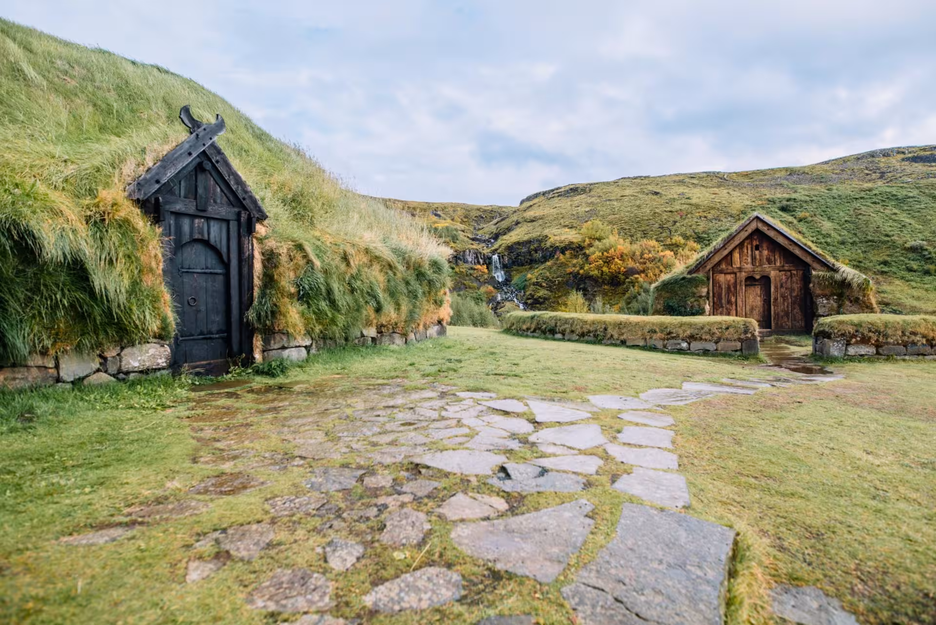 Private Þjórsárdalur Valley Tour view of restored turf houses at Stöng with stone path and valley waterfall