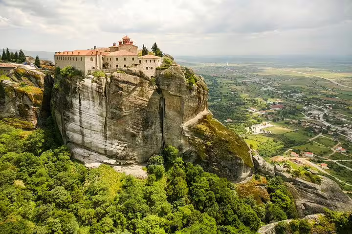 Monastery atop Meteora cliffs overlooking Kalabaka valley, highlight view on private transfer from Athens