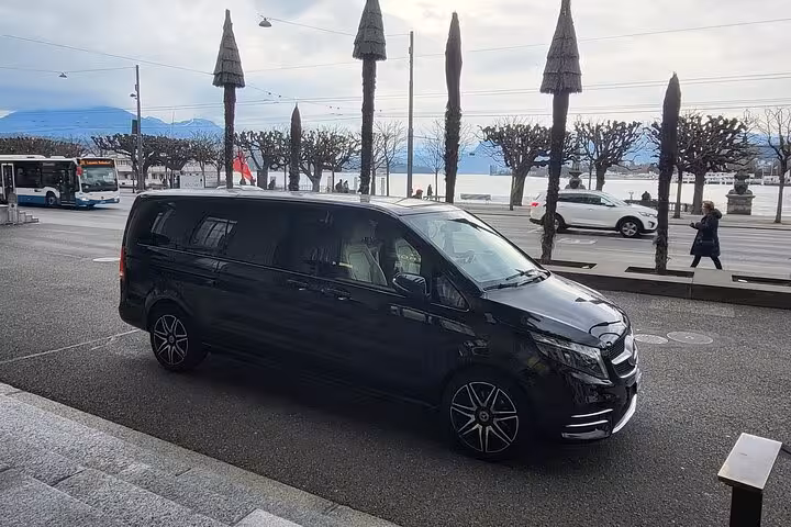 Private Luzern to Zurich transfer van parked by Lake Lucerne promenade, comfortable executive chauffeur service