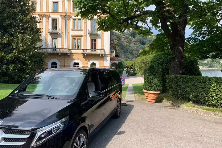 Luxurious black van parked near a historic building, highlighting private transfer service from Malpensa Airport to Milan.
