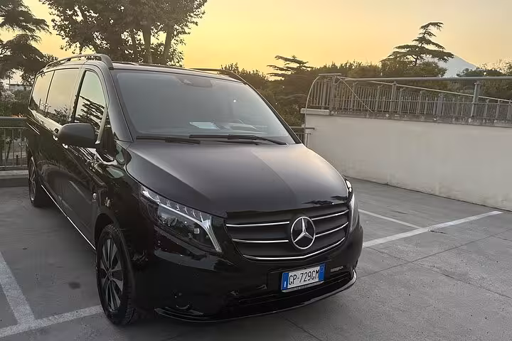 Luxurious black Mercedes van ready for private transfer from Naples to Sorrento at sunset.