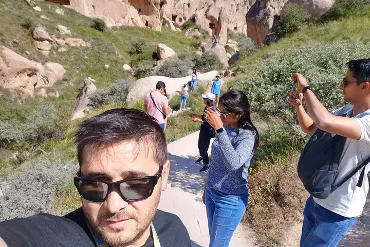 Travelers on private 6-day Turkey tour hiking Cappadocia valley trail, taking photos of rock formations