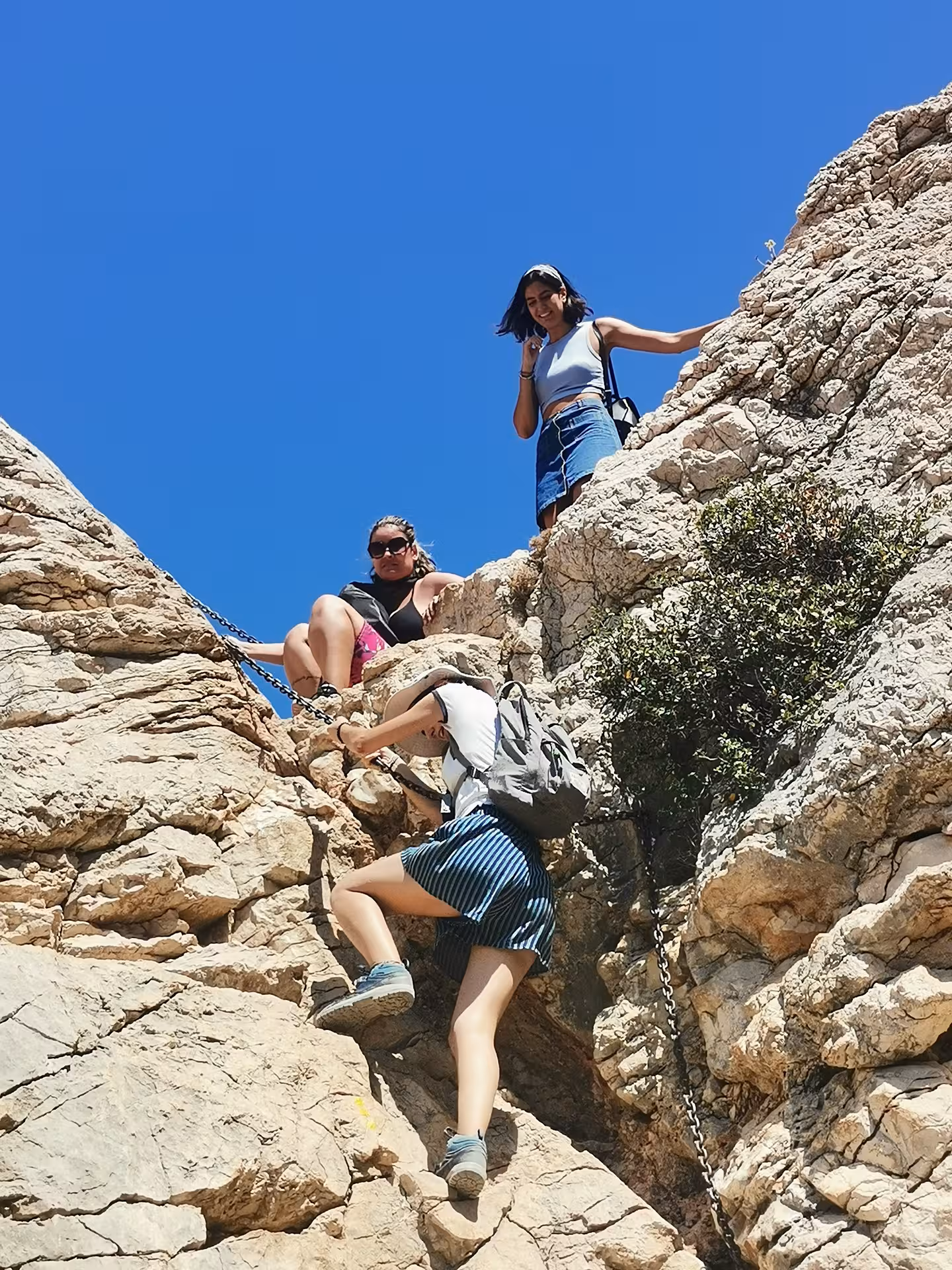 Hikers scrambling up chain-assisted limestone rocks in Calanques National Park on a 7-day Provence trek