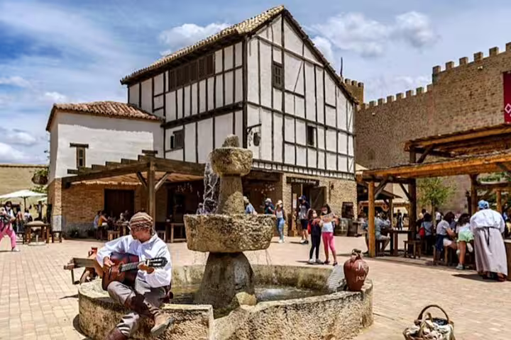 Puy du Fou village square with stone fountain and medieval buildings, easy minivan transfer service
