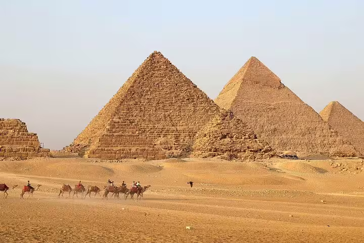Panoramic view of the Pyramids of Giza with camel caravan in the desert, classic Cairo sightseeing tour stop