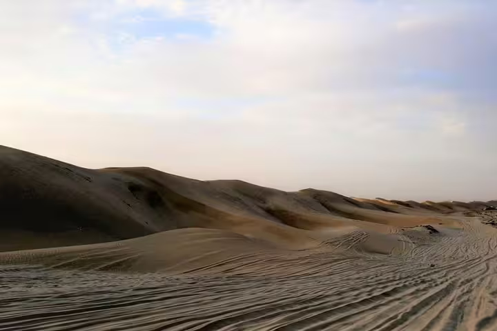 Scenic view of Qatar's rolling desert dunes under a vast blue sky, perfect for a thrilling desert safari adventure.
