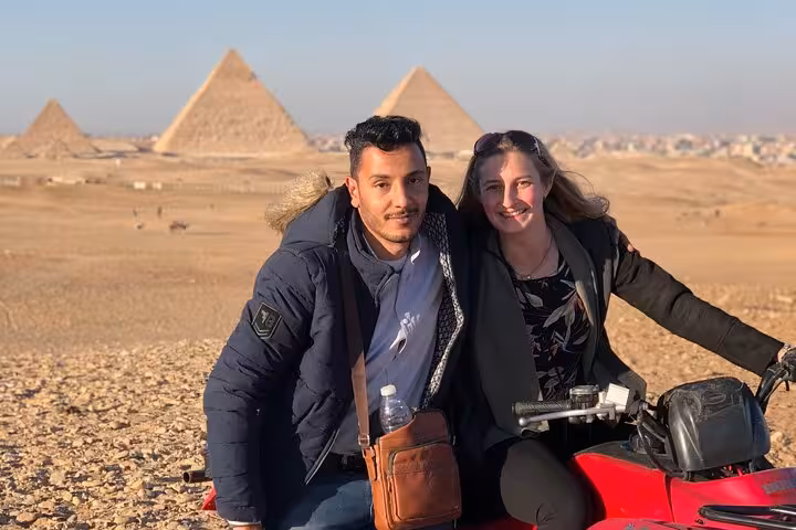 Couple posing on quad bike in front of Giza Pyramids, desert ATV safari tour with hotel transfers and drinks