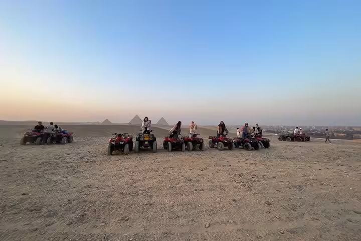 Group quad biking in the Giza Desert with pyramids in the distance, guided ATV safari with transfers and drinks