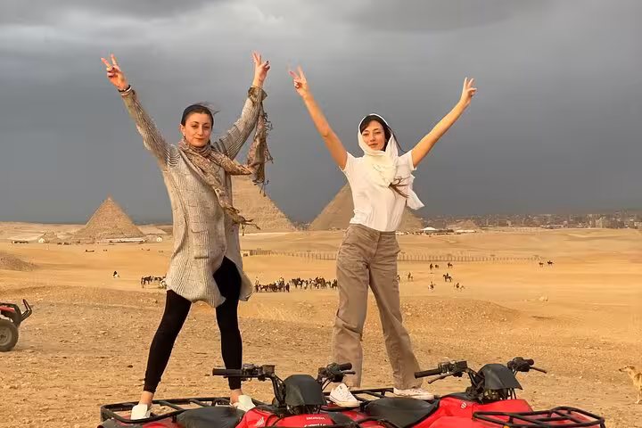 Friends posing on quad bikes in Giza Desert with pyramids backdrop, ATV tour with hotel transfers and drinks