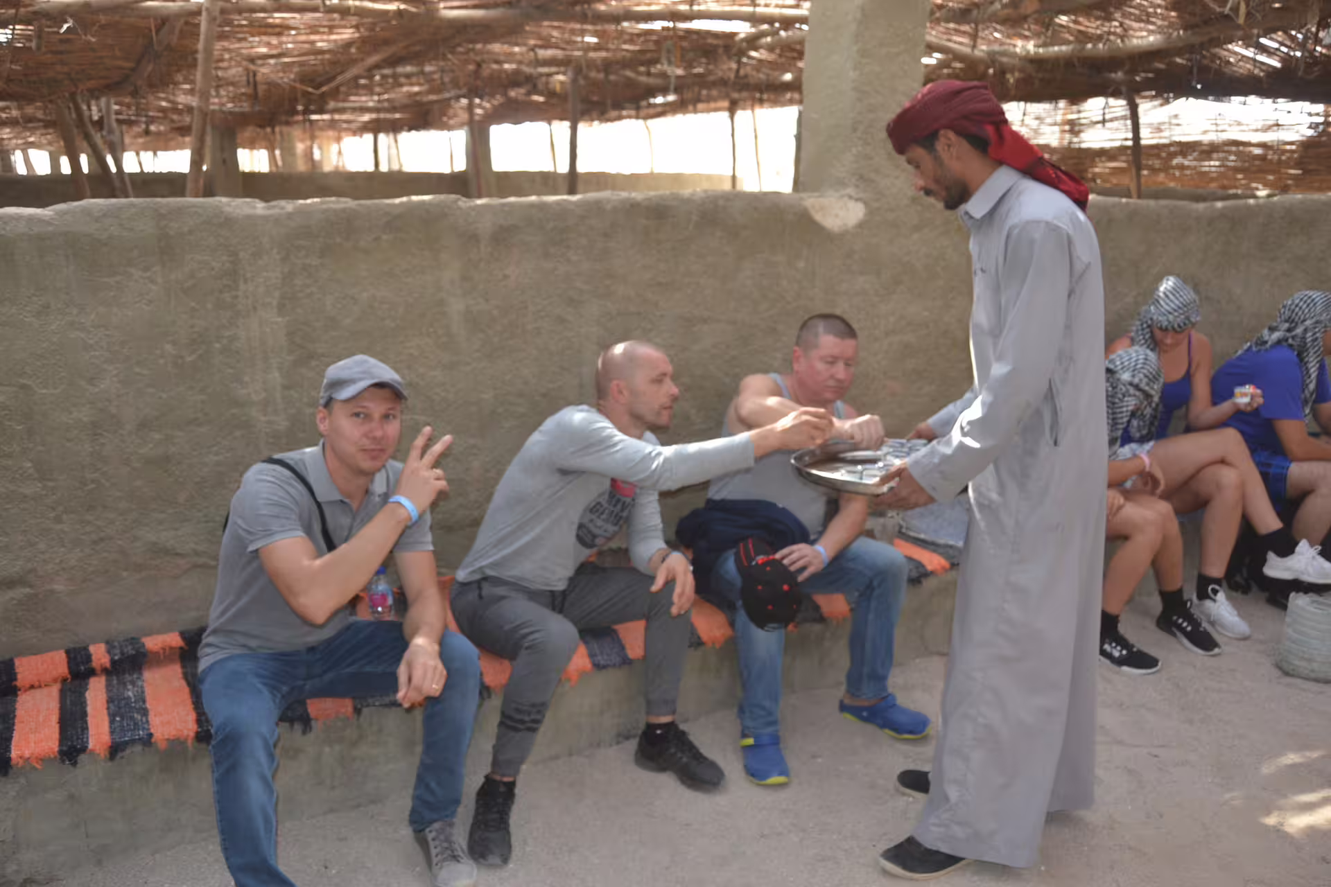 Bedouin tea break during Hurghada quad safari, tourists seated in desert camp while host serves drinks