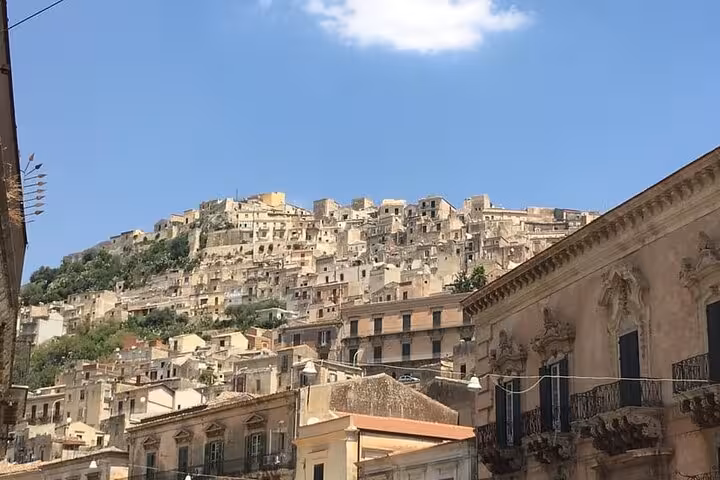 Sunlit hillside of Ragusa Ibla showcasing stunning Baroque buildings under a clear blue sky.