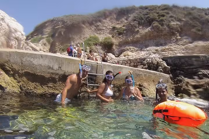 Snorkeling stop on the Rando-Palmée island tour, group in clear water by rocky cove and ladder