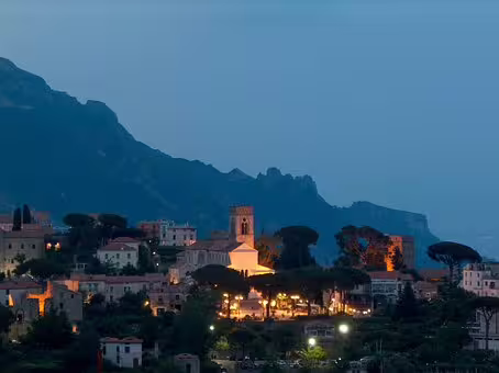 Twilight view of Ravello on the Amalfi Coast from Salerno tour, with church tower and village lights glowing against mountains
