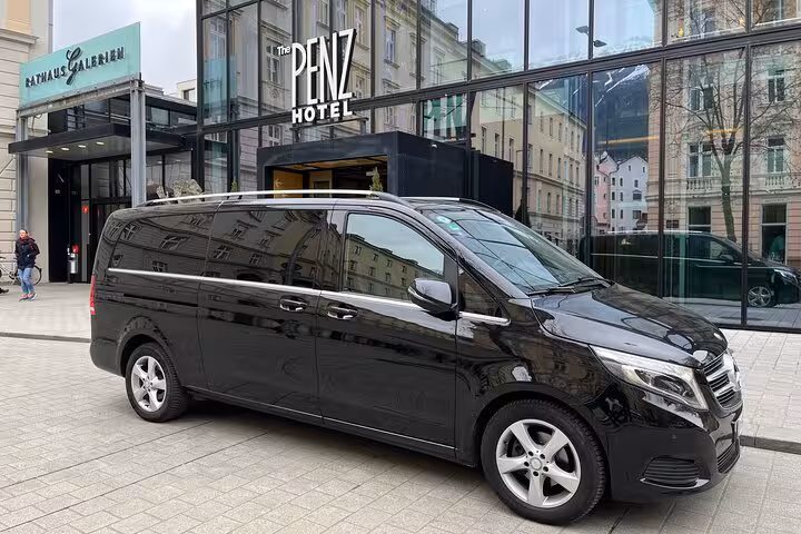Spacious black van outside modern hotel entrance, ready for Ravenna cruise terminal to Bologna Airport transfers.