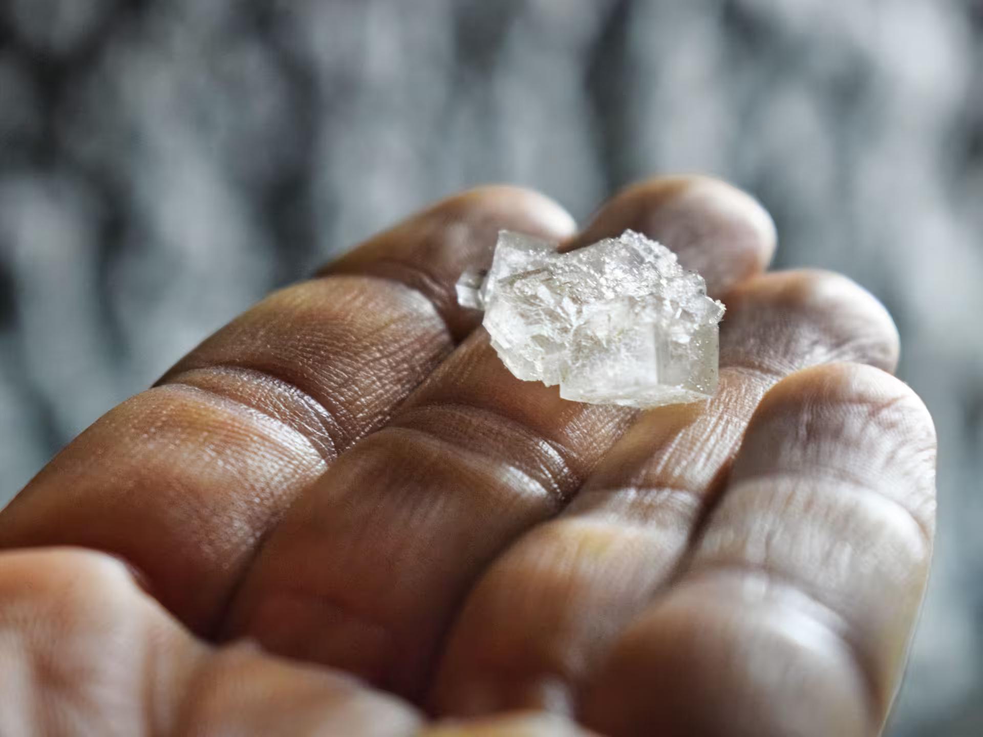 A raw salt crystal held in hand, showcasing natural minerals found during Turda Salt Mine full-day tour in Romania.