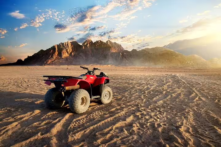 Red ATV quad bike in Marsa Alam desert at sunset, part of ATV ride, camel trek and Bedouin dinner show