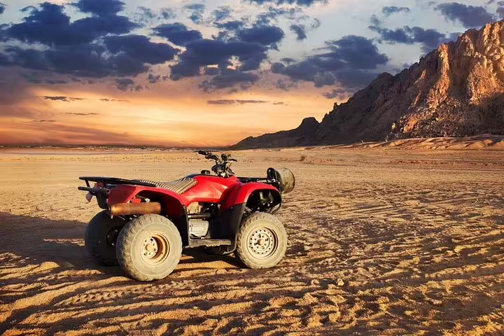 Red ATV quad bike parked in Sinai desert at sunset near Sharm el Sheikh, before camel ride and Bedouin dinner show