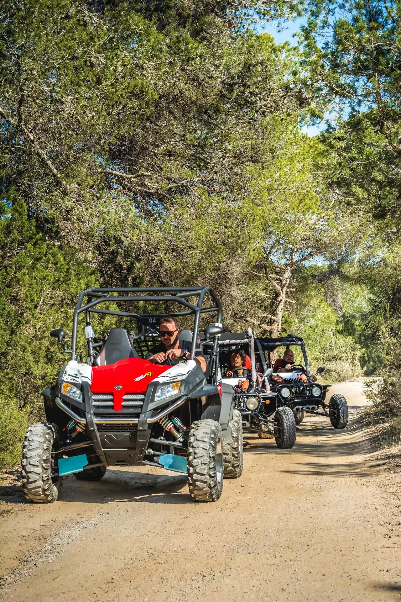 Red off-road buggy leading group through pine forest on Ibiza day trip, southern Ibiza nature and Salinas tour