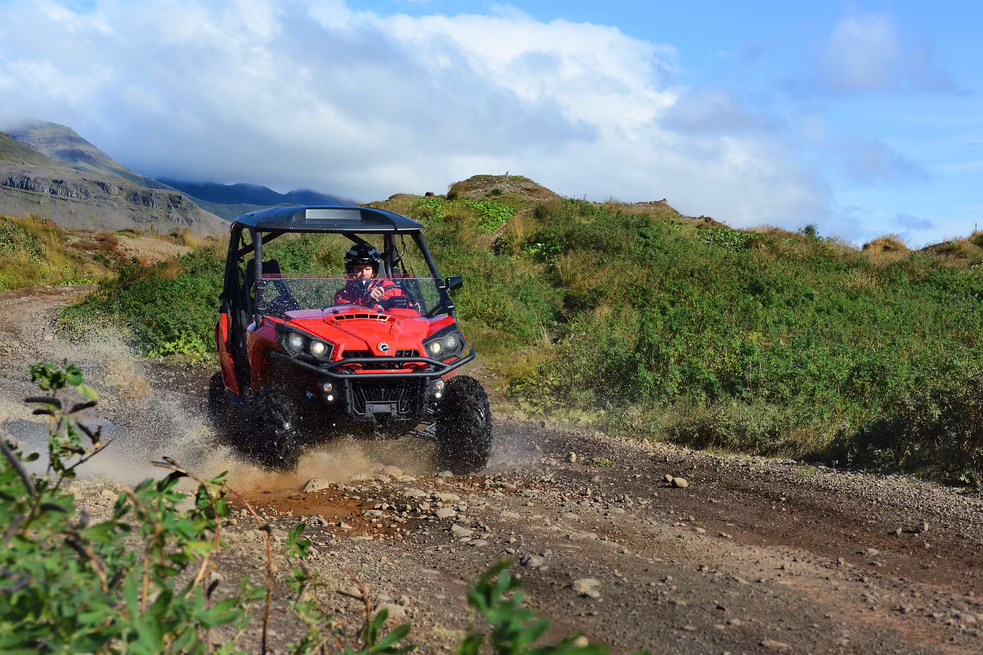 Adventurer driving a red buggy through rugged lava fields under a clear sky, perfect for a thrilling 2-hour off-road tour.