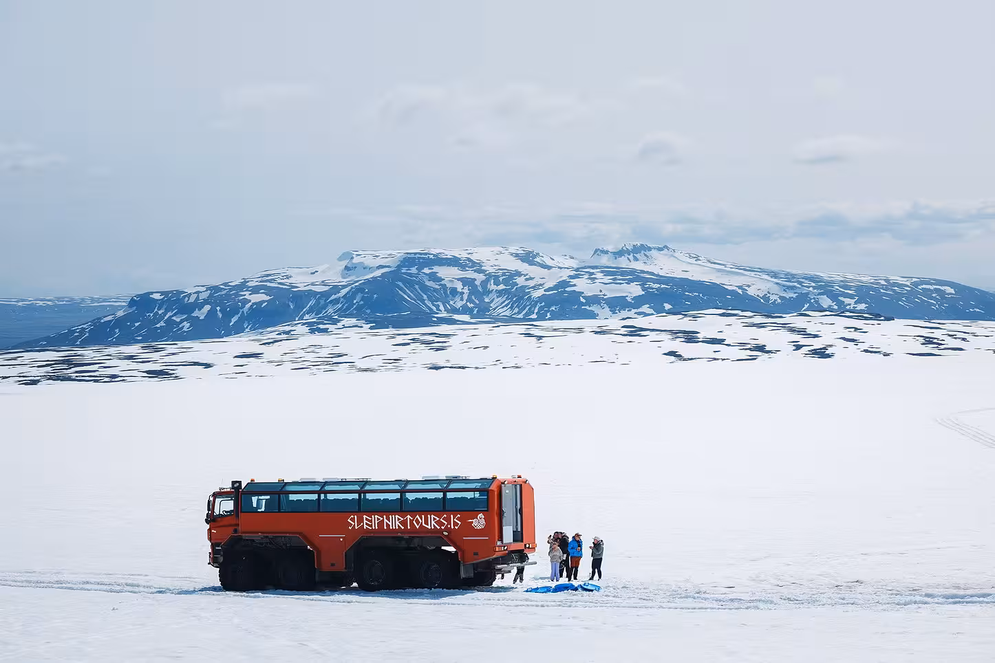 Red Glacier Monster Truck parked on Langjökull glacier with tour group, ice cave and glacier trip from Gullfoss