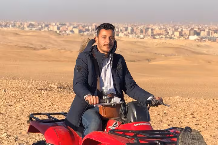 Rider on red quad bike in Giza desert dunes near Cairo, pyramid ATV tour with hotel transfers and drinks