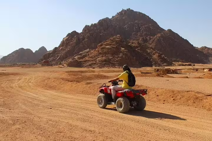 Rider on red quad bike crossing sandy Sinai Desert near Sharm El Sheikh on a private ATV adventure tour