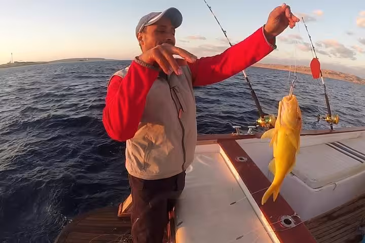 Red Sea boat trip in Hurghada with traveler holding a fresh catch, add-on activity from Luxor day tour