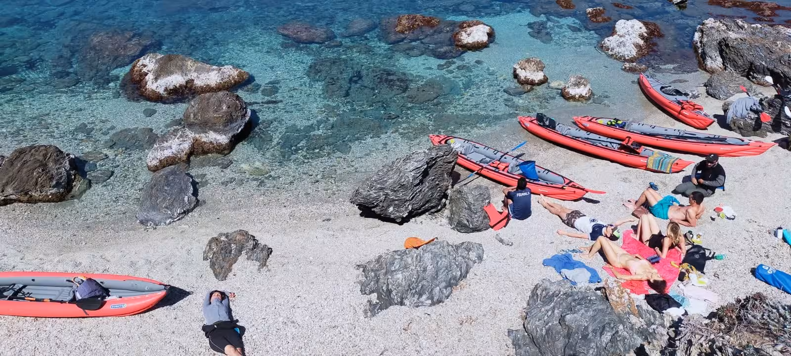 Red sea kayaks on a pebble cove with turquoise water, stop on the Embiez Islands naturalist kayak tour