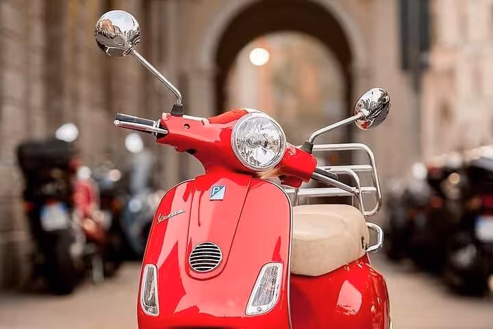 Close-up of a red Vespa scooter parked on a cobblestone street, perfect for Chianti small group Vespa tours.