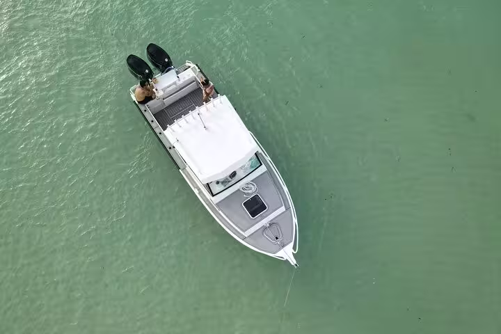 Aerial view of a private boat on clear turquoise waters, ideal for a secluded snorkeling adventure on a day trip.