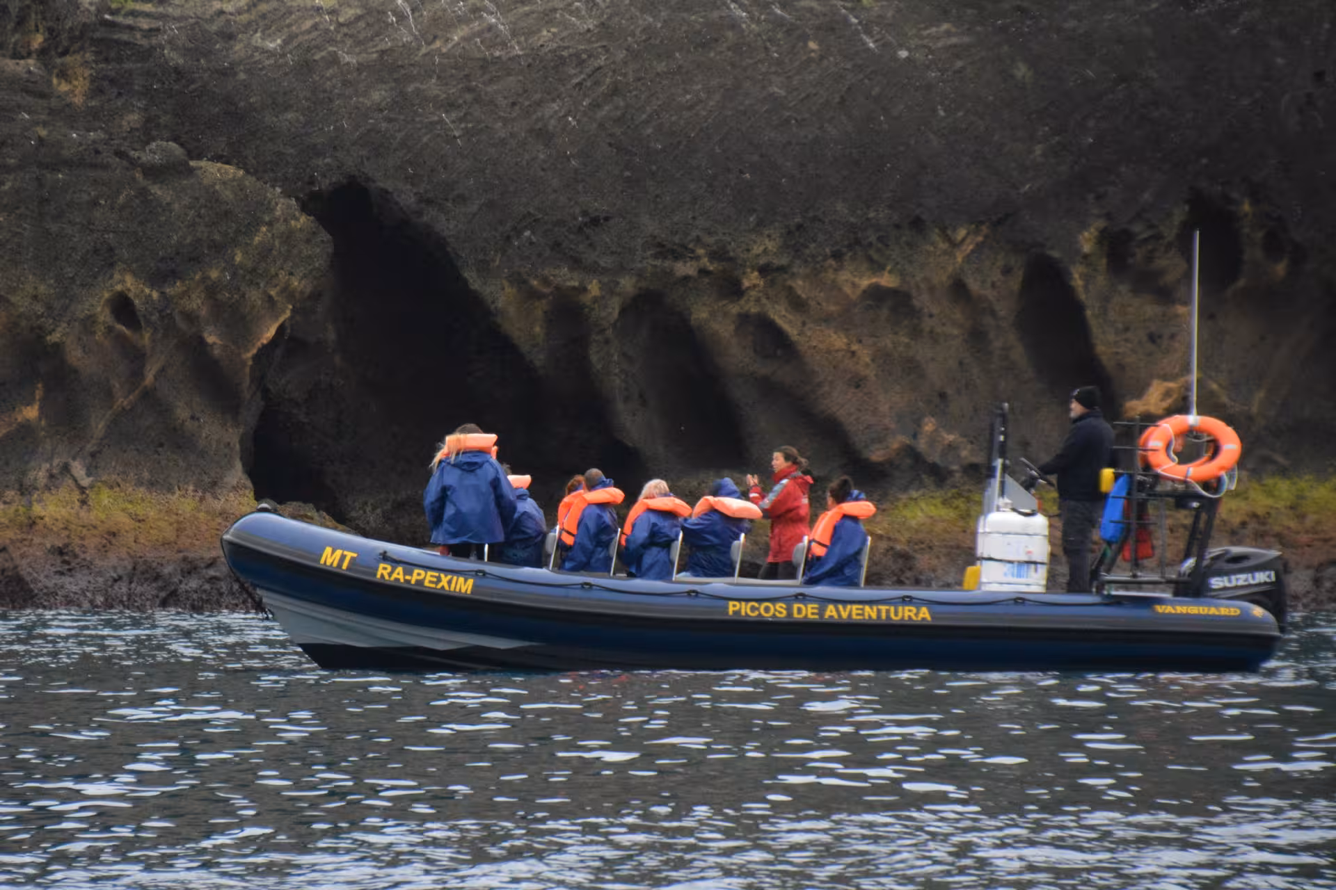 RIB boat exploring volcanic sea caves on a full-day maritime experience tour, guests in jackets and guide onboard