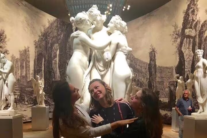 Visitors pose by classical marble statues in Rijksmuseum gallery on Stories Behind the Masterpieces tour